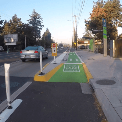 A transit stop on Division street where a bike lane passes through near the bus stop waiting area