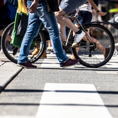 Pedestrians and cyclists cross a street at a marked crosswalk.