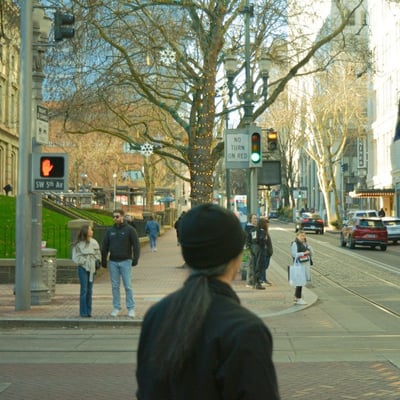 People waiting at a crosswalk intersection outside of Pioneer Place in Portland, Oregon.